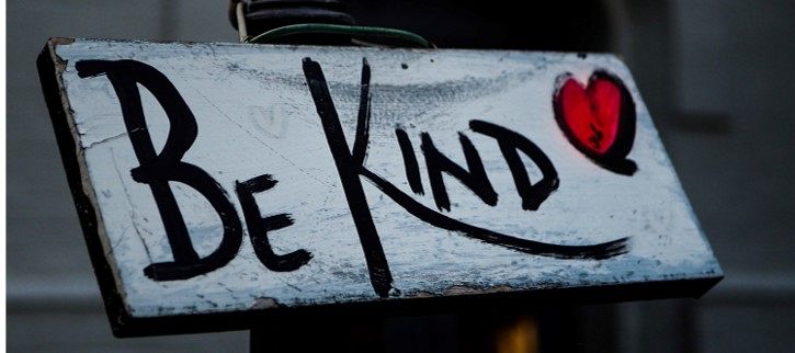 A hand-painted wooden sign reading Be Kind, with a red heart