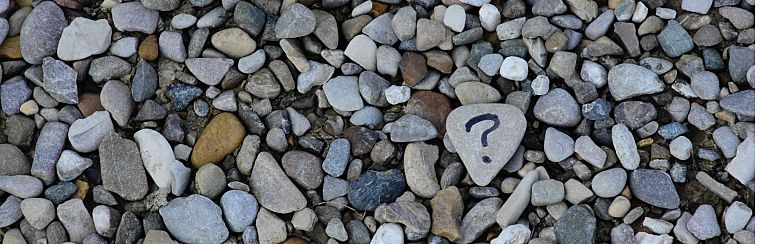 A question mark painted on a pebble among many plain pebbles