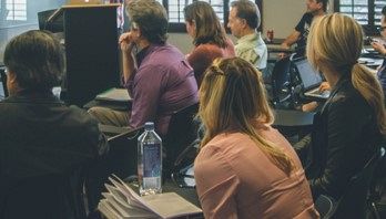 People seated in rows, listening during a meeting