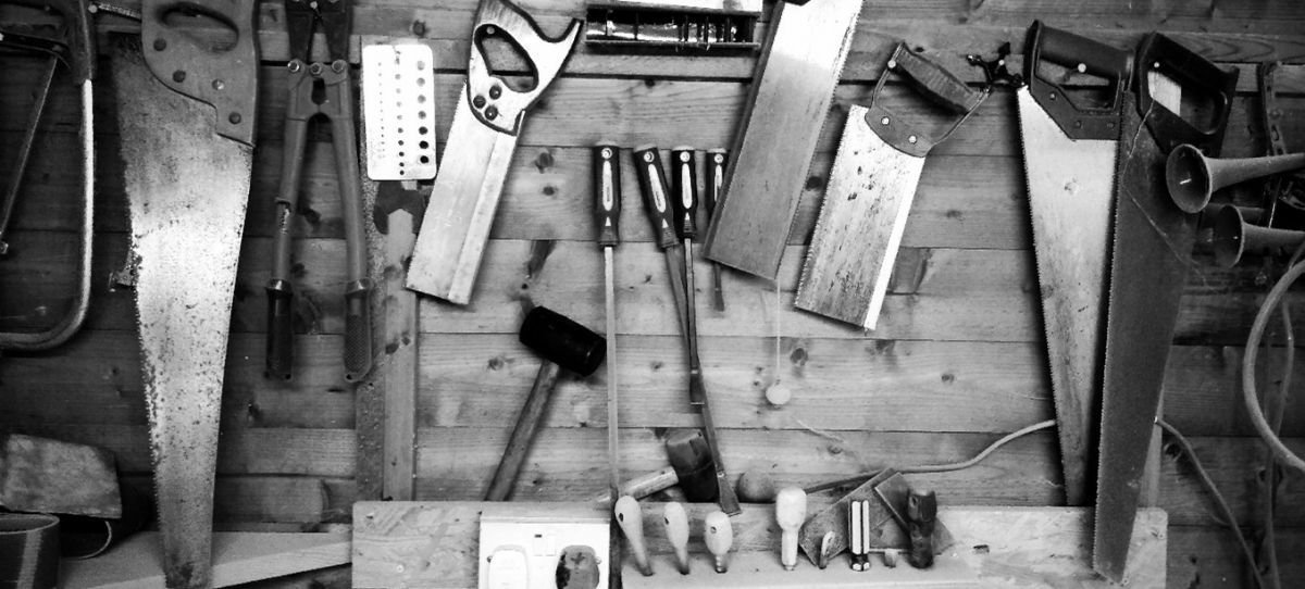 Saws, chisels and a mallet hung in neat rows on a workshop wall